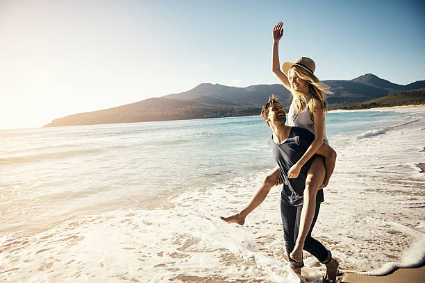 Expressions of true love Shot of a young couple enjoying a piggyback ride at the beach honeymoon stock pictures, royalty-free photos & images