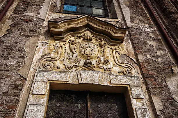 Coat-of-arms with date of last renovation above rusty church door