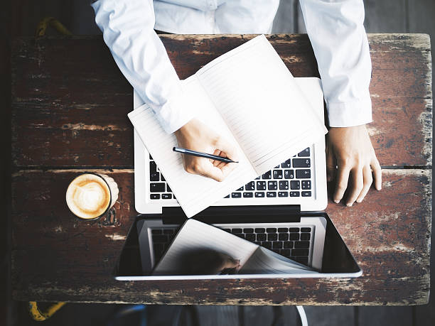 istock Man writing in notepad with laptop and coffee mug 522132712