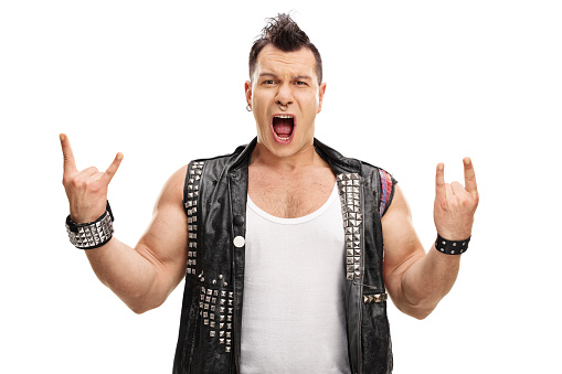 Excited punk rocker making rock hand gesture and looking at the camera isolated on white background