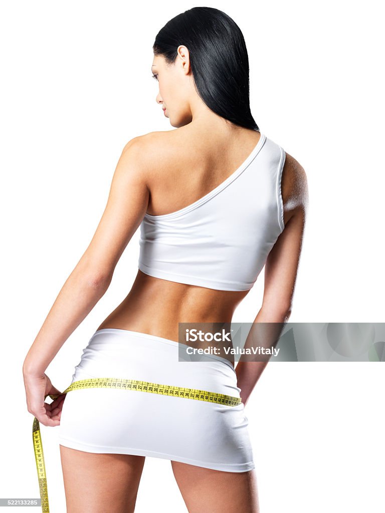 Sporty woman with slim body measuring hips Rear view of sporty woman with slim body measuring hips - model posing in studio Adult Stock Photo