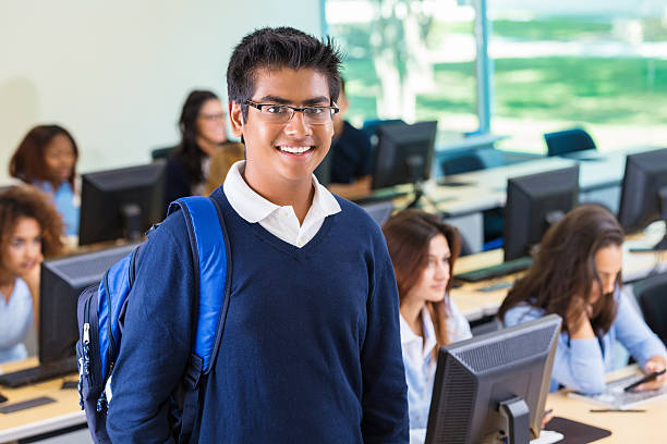 Indian American college prep school student in computer lab Teenage student holding laptop in high school computer lab school boy in uniform stock pictures, royalty-free photos & images