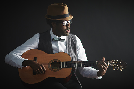 Young African musician playing guitar and singing
