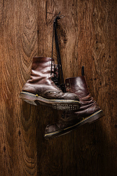 Vertical shot of an old pair of brown boots hanging on a wooden wall