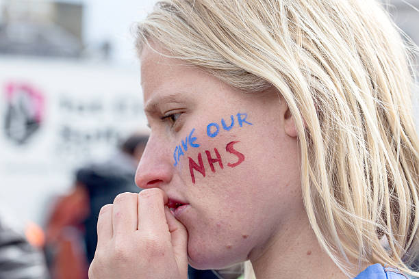 Anti-Austerity March.  London, United Kingdom - April 16, 2016: A junior doctor at the anti-austerity march in London, contemplates the speeches being made in Trafalgar Square. socialist symbol stock pictures, royalty-free photos & images