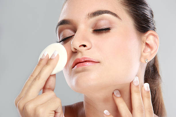 istock woman smiling while applying powder puff 522139968