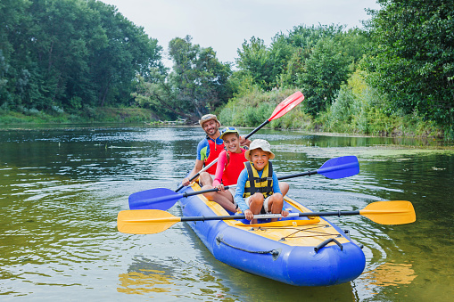 Active happy family. Boy with his sister and father having fun together enjoying adventurous experience kayaking on the river on a sunny day during summer vacation