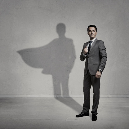 Businessman with a superhero shadow on the wall