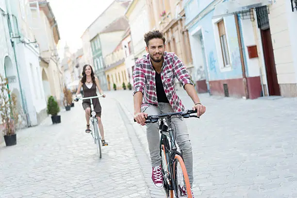 smiling friends enjoying the sunset in the city, riding their bikes on a historical street