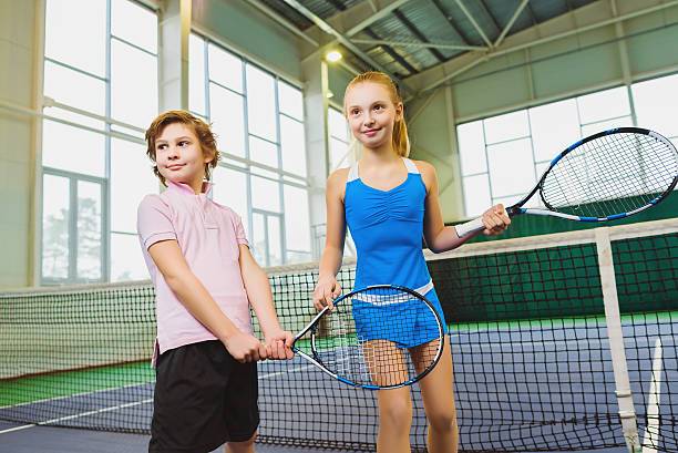 Children playing tennis and posing indoor stock photo
