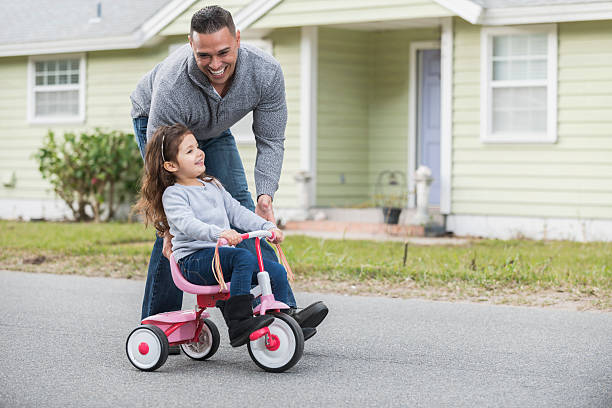 istock Hispanic father helping daughter ride tricycle 522147562