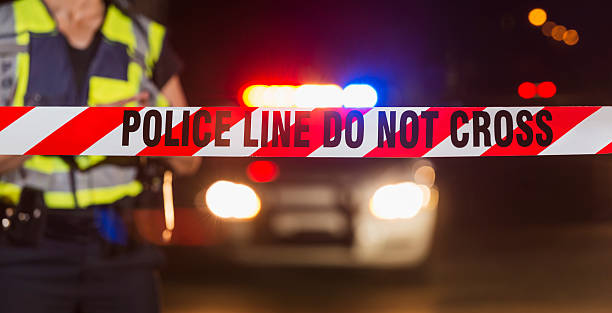 istock Policewoman standing behind crime scene tape 522149034