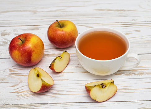 Cup of tea and apples on wooden background