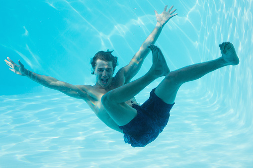 Full length portrait of a young man swimming underwater