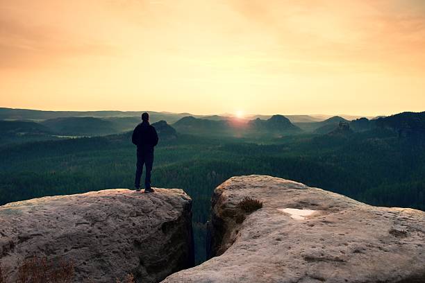 istock Hiker on sharp cliff watching over misty morning gulch 522150758