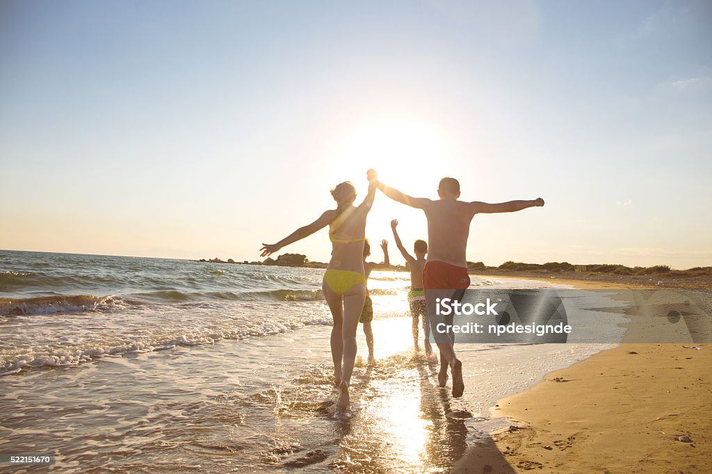Young family on the beach Mother, father and children jump into the sea.  Aquatic Organism Stock Photo