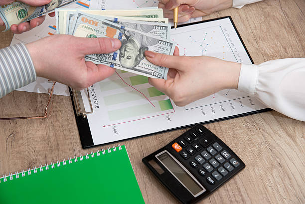 istock Human hands exchanging money above business graph 522152032