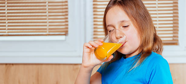 istock Little girl drinks orange juice 522165839
