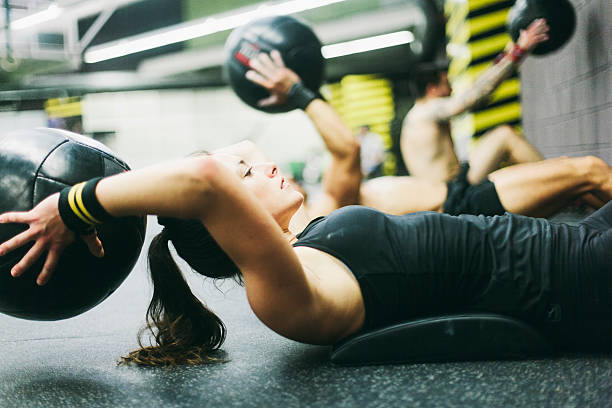 Young woman in high intensity fitness session. One young woman working hard in the gym. More files of this series on port. She is doing pushups from a a fit bench.  cross training stock pictures, royalty-free photos & images