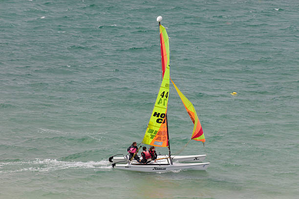 Teenagers catamaran sailing on Atlantic Ocean Saint-Malo, France - July 6, 2011: Three teenagers catamaran sailing on the coast of Saint-Malo. Their Hobie Cat 15 catamaran is developed for the use in sailing schools. This catamarans is 15 feet long and has a great buoyancy. leisure activity french culture sport high angle view stock pictures, royalty-free photos & images