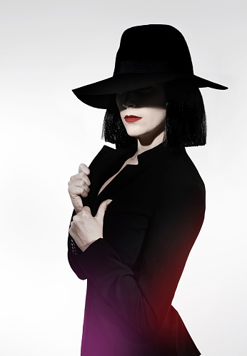 Studio shot of a mysterious woman wearing a hat against a gray background