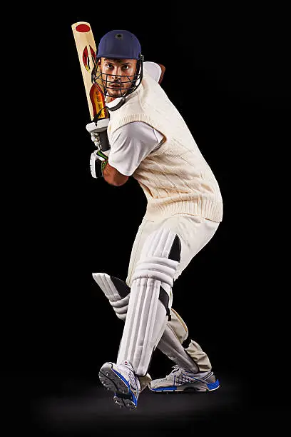 A cropped shot of an ethnic young man in cricket attire isolated on black