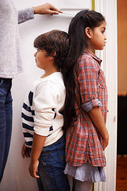They grow up so fast Shot of a mother measuring her children's height against a wallhttp://195.154.178.81/DATA/shoots/ic_784169.jpg boy height measure stock pictures, royalty-free photos & images