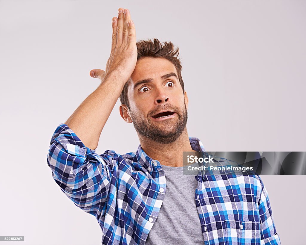 Duh! Studio shot of a young man looking forgetful against a gray background Reminder Stock Photo