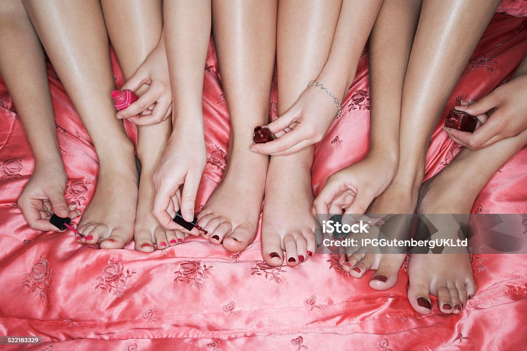 Painting Toenails On Pink Bedsheet Closeup of teenage girls painting toenails on pink bedsheet Adolescence Stock Photo