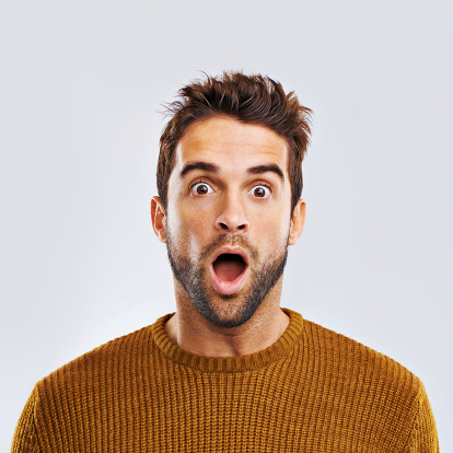 Portrait of a shocked young man against a gray background