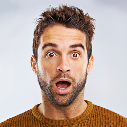 Portrait of a shocked young man against a gray background