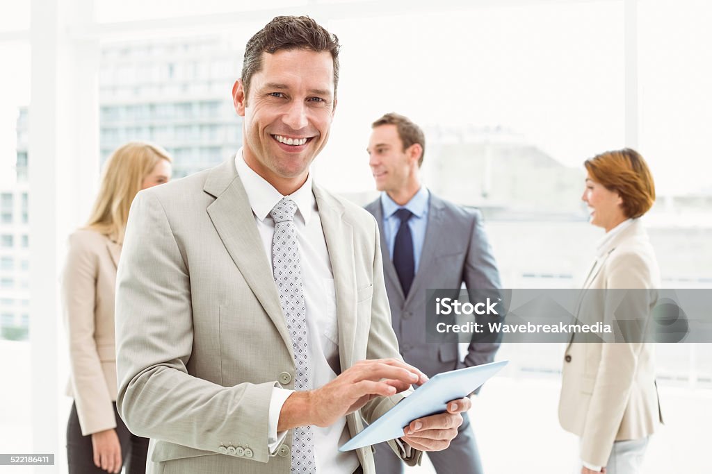 Businessman using digital tablet with colleagues behind Portrait of businessman using digital tablet with colleagues behind in office 20-29 Years Stock Photo