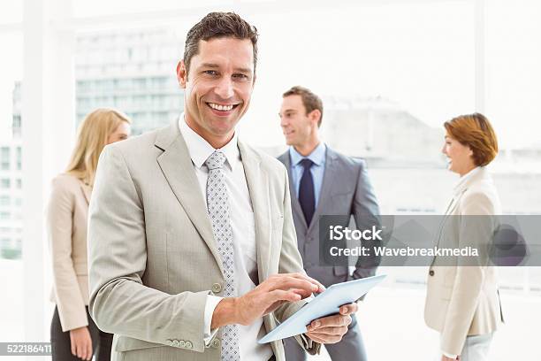 Businessman Using Digital Tablet With Colleagues Behind Stock Photo - Download Image Now