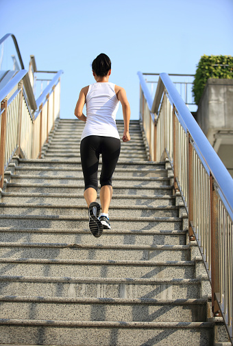 Runner athlete running on escalator stairs. woman fitness jogging workout wellness concept.