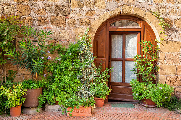 Gubbio, Umbria, Italy -- A typical door of a medieval stone house in the historic heart of Gubbio in Umbria, central Italy. Ancient allied city of Rome and born on the communication routes between the Tyrrhenian coast and the Adriatic coast, Gubbio is famous for its artistic treasures and considered the most beautiful medieval villages in Italy. This Umbrian town is also known for the life of St. Francis of Assisi and the miracle of the encounter between him and a wolf. Gubbio is also famous for the traditional and ancient race of the Festa dei Ceri, which takes place every year in May. The Umbria region is the green lung of Italy for its wooded mountains, characterized by a perfect integration between nature and the presence of man, in a context of environmental sustainability and healthy life. In addition to its immense artistic and historical heritage, Umbria is famous for its food and wine production and for the high quality of the olive oil produced in these lands. Image in original 4:3 ratio.