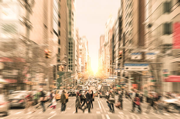 People on the street in Manhattan - New York City People on the street on Madison Avenue in Manhattan downtown before sunset in New York city - Commuters walking on zebra crossing during rush hour in american business district - Radial defocusing added during editing to make all the people completely unrecognizable times square manhattan photos stock pictures, royalty-free photos & images