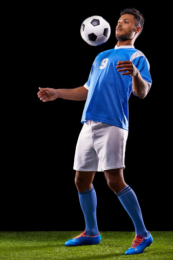 Full length studio shot of a handsome young soccer player isolated on black