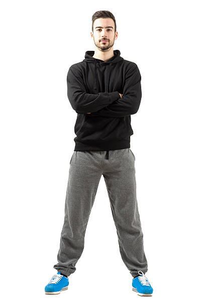 Young male with folded or crossed hands in the sportswear Young male with folded or crossed hands in the sportswear. Full body length isolated over white background. jogging pants stock pictures, royalty-free photos & images