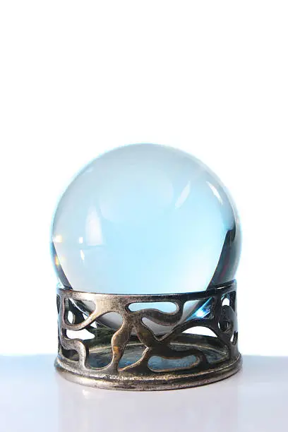 Blue light in a cystal ball in stand against a white background
