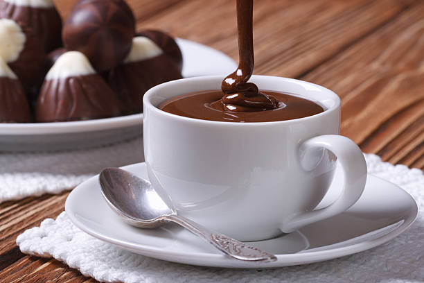 chocolate é vertida em um copo no plano de fundo de doces - chocolate chocolate candy dark chocolate pouring imagens e fotografias de stock