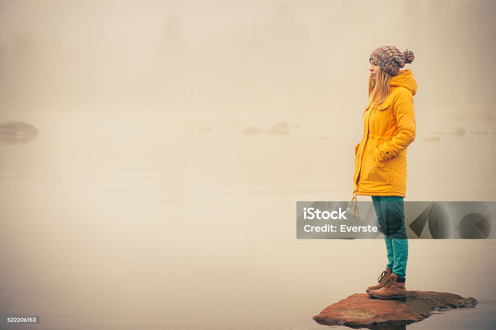 Young Woman standing alone outdoor Travel Lifestyle Young Woman standing alone outdoor Travel Lifestyle and melancholy emotions concept  winter foggy nature on background Adolescence Stock Photo