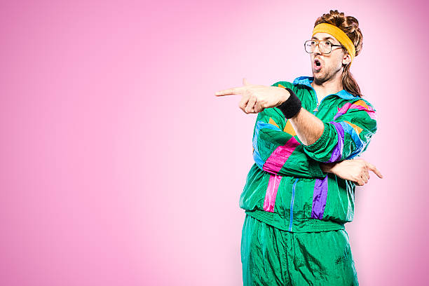 Mullet Man With Eighties Fashion Style A cool, funky young adult in late 1980's / early 1990's fashion style, with mullet, fluorescent colored track suit, nerdy glasses, and sweat band.  He points, gesturing like he is rapping, or yelling at someone. Vibrant pink background. Horizontal with copy space. 1990s style stock pictures, royalty-free photos & images