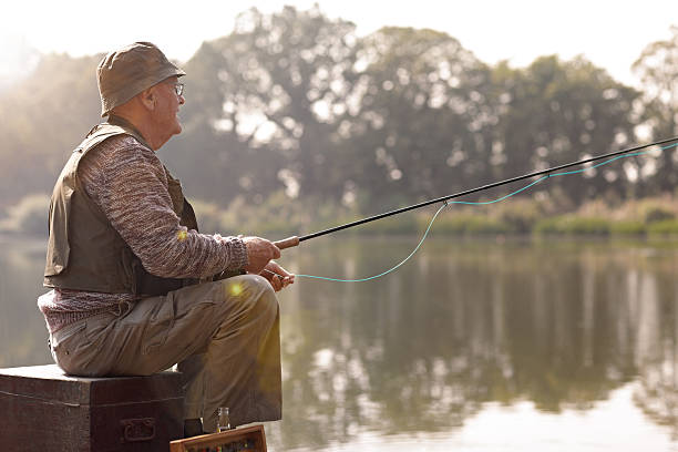 starszy człowiek połowów na jeziorze - fishing fishing industry fly fishing river zdjęcia i obrazy z banku zdjęć