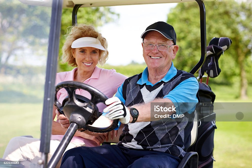 Senior couple driving a golf cart Portrait of senior couple driving a golf cart on a golf course looking happy. 50-59 Years Stock Photo