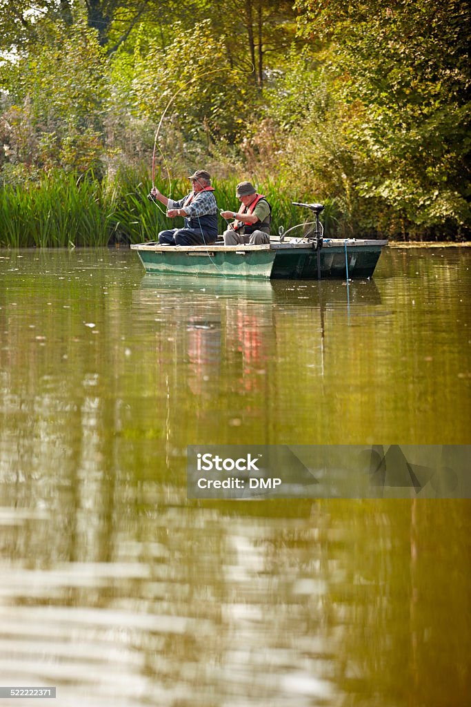 Two mature men fishing on a lake Two mature men fishing on a lake from a small boat Catch of Fish Stock Photo