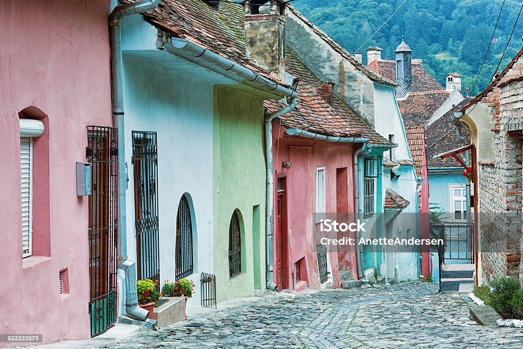 Cobblestone street in Sighisoara, Romania. Picturesque alley with pastel coloured buildings in the medieval city Sighisoara in Transylvania. Pastel Colored Stock Photo