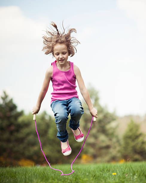 Young girl skipping in park stock photo