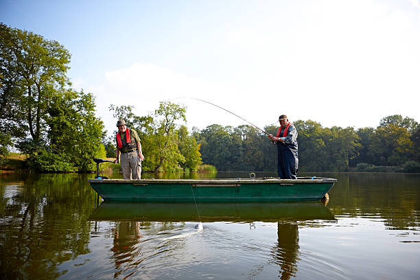 dois homens idosos pesca em um lago - fishing nautical vessel small men imagens e fotografias de stock