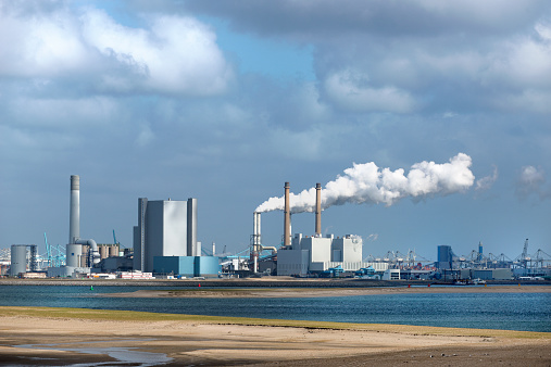 energy plant in holland, Europoort near Rotterdam. Skyline of the harbor under a dramatic sky, In the front the beach of the North Sea.