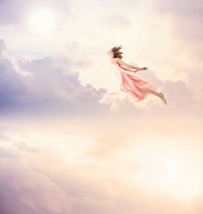 Girl in a pink dress flying in the sky. Serenity.